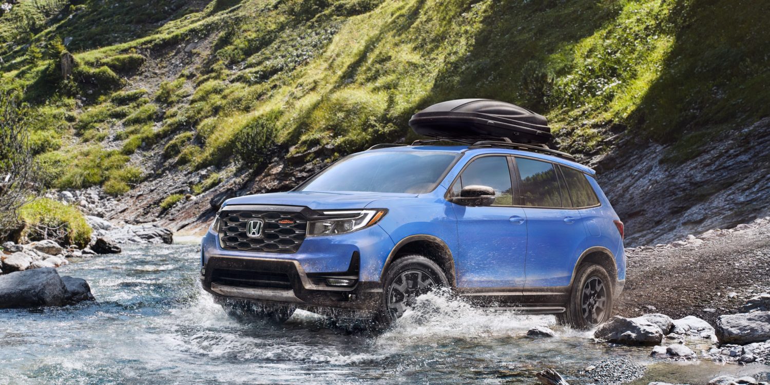 Three-quater view of a 2024 blue Honda Passport Trailsport crossing a river