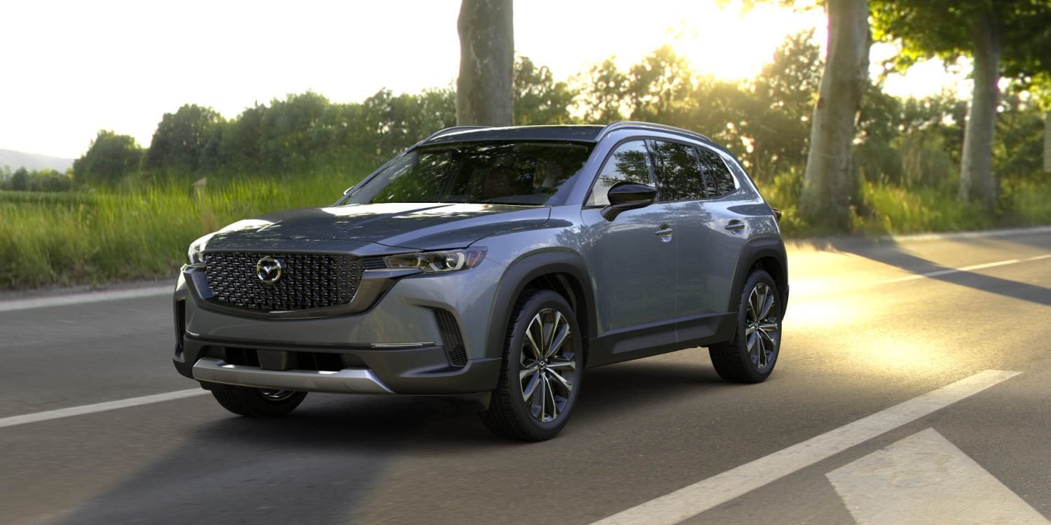 Three-quarter front view of a 2024 grey Mazda CX-50 with sunset background