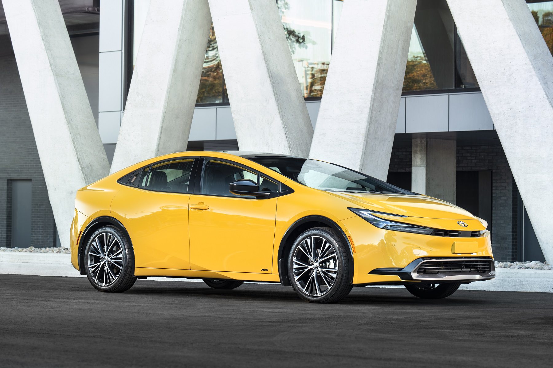 Three-quater side view of a 2024 yellow Toyota Prius on a city street